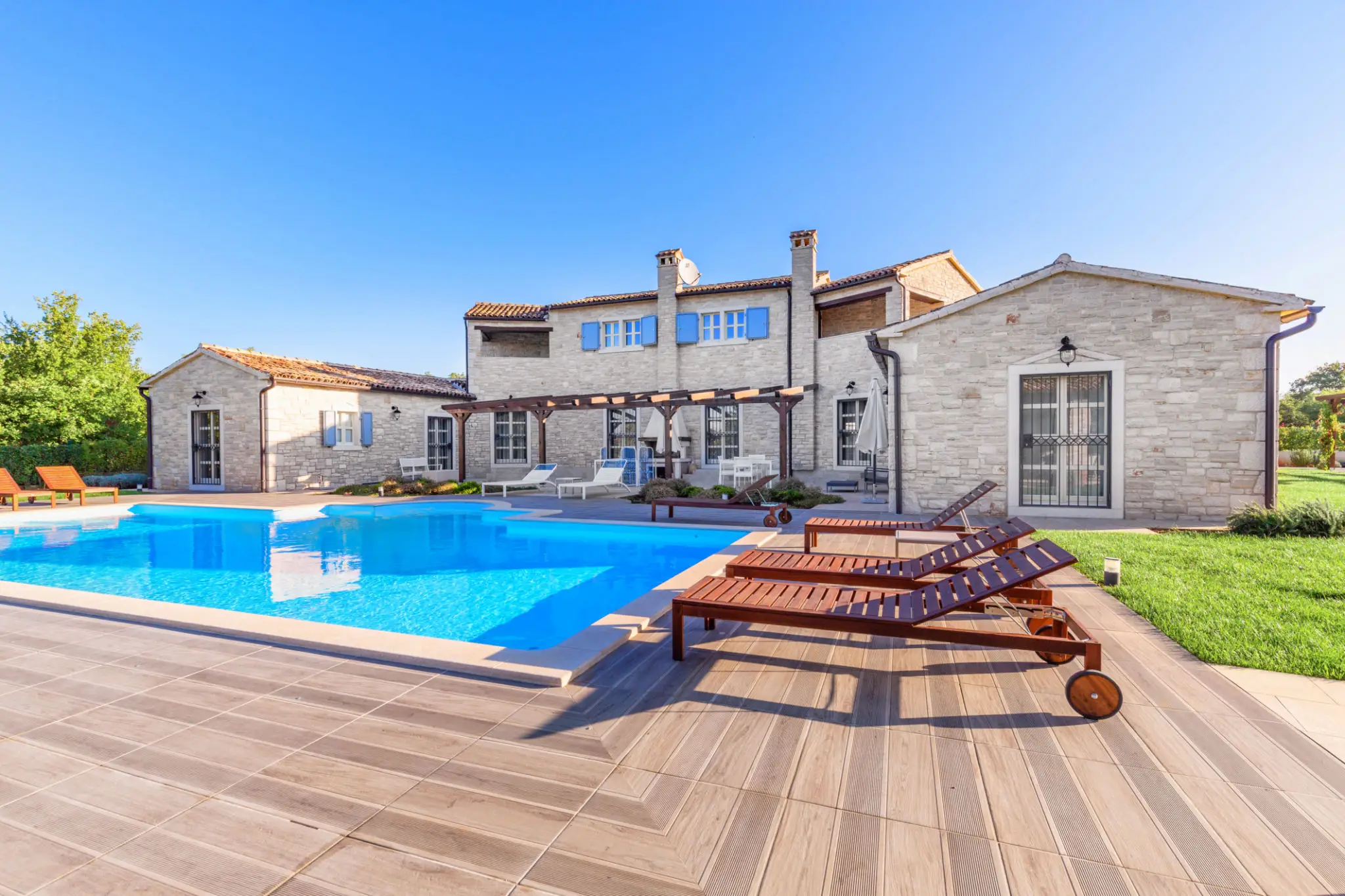 Luxury villa with pool and sun loungers.