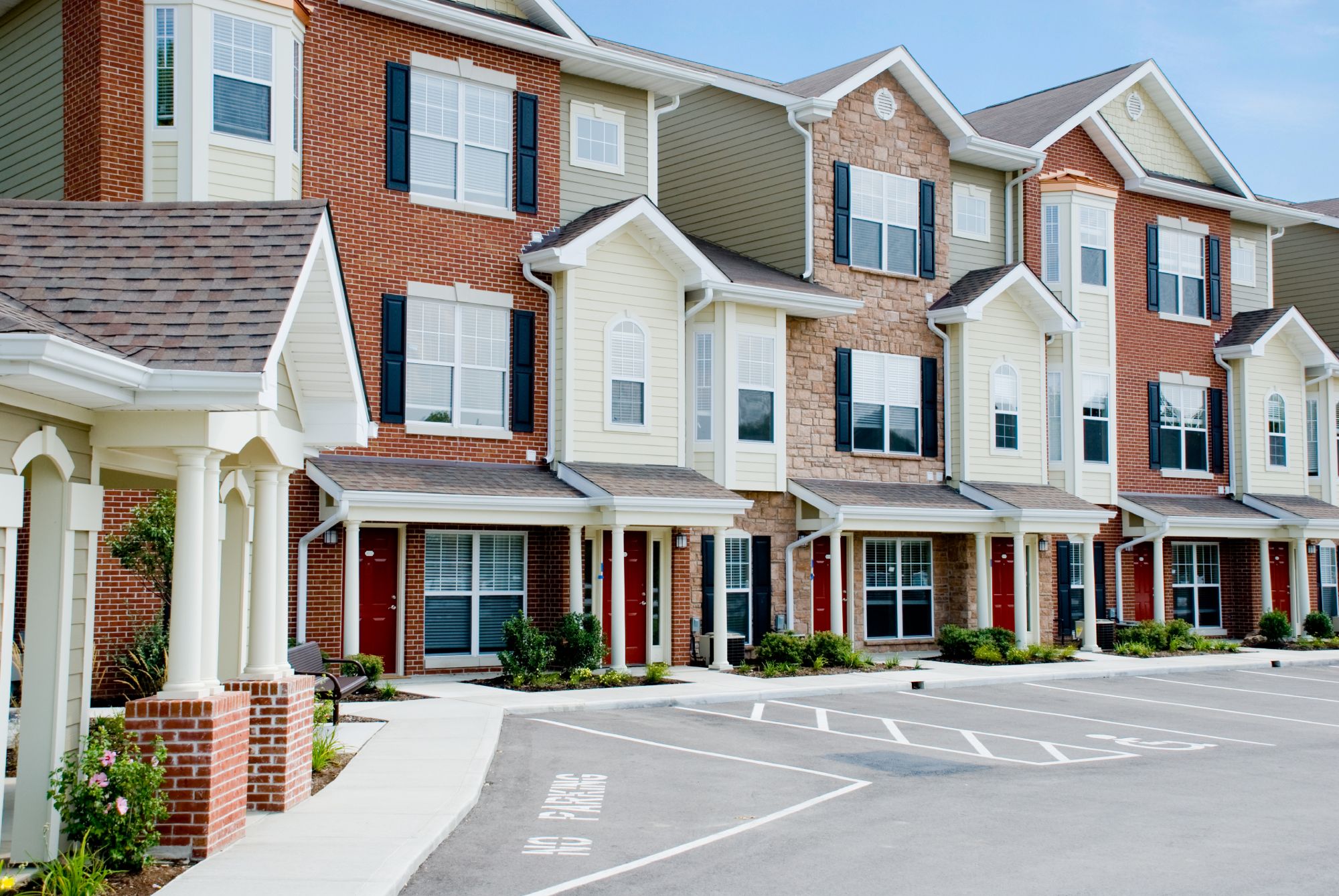 Row of modern townhouses with parking area.