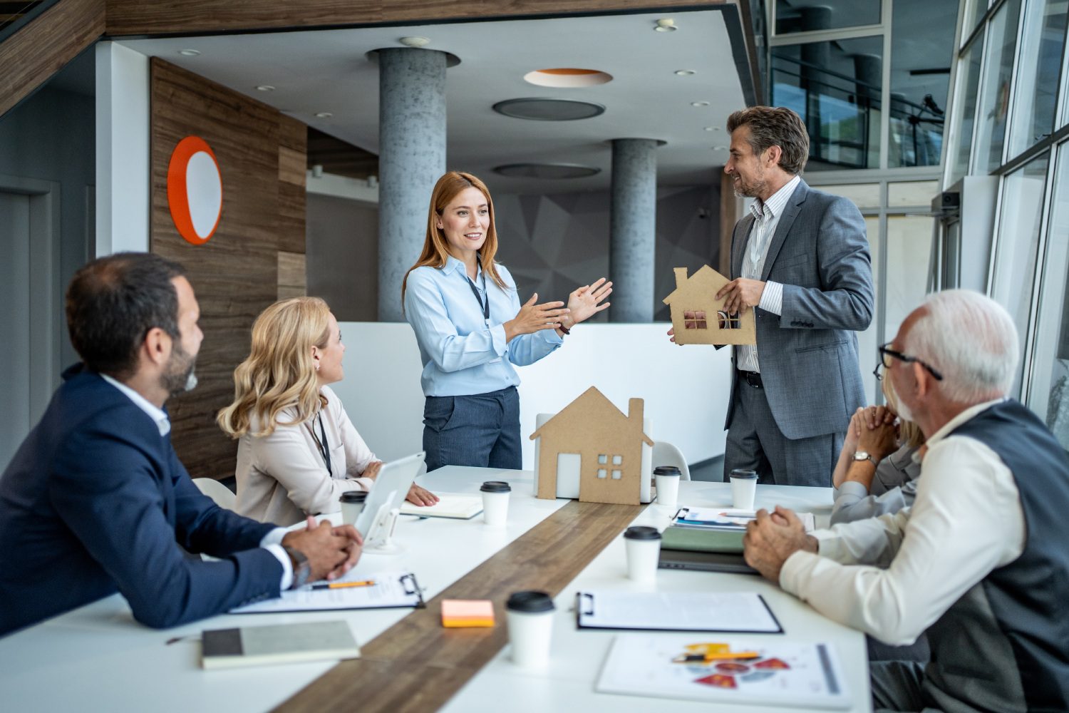 Business meeting discussing real estate model house.